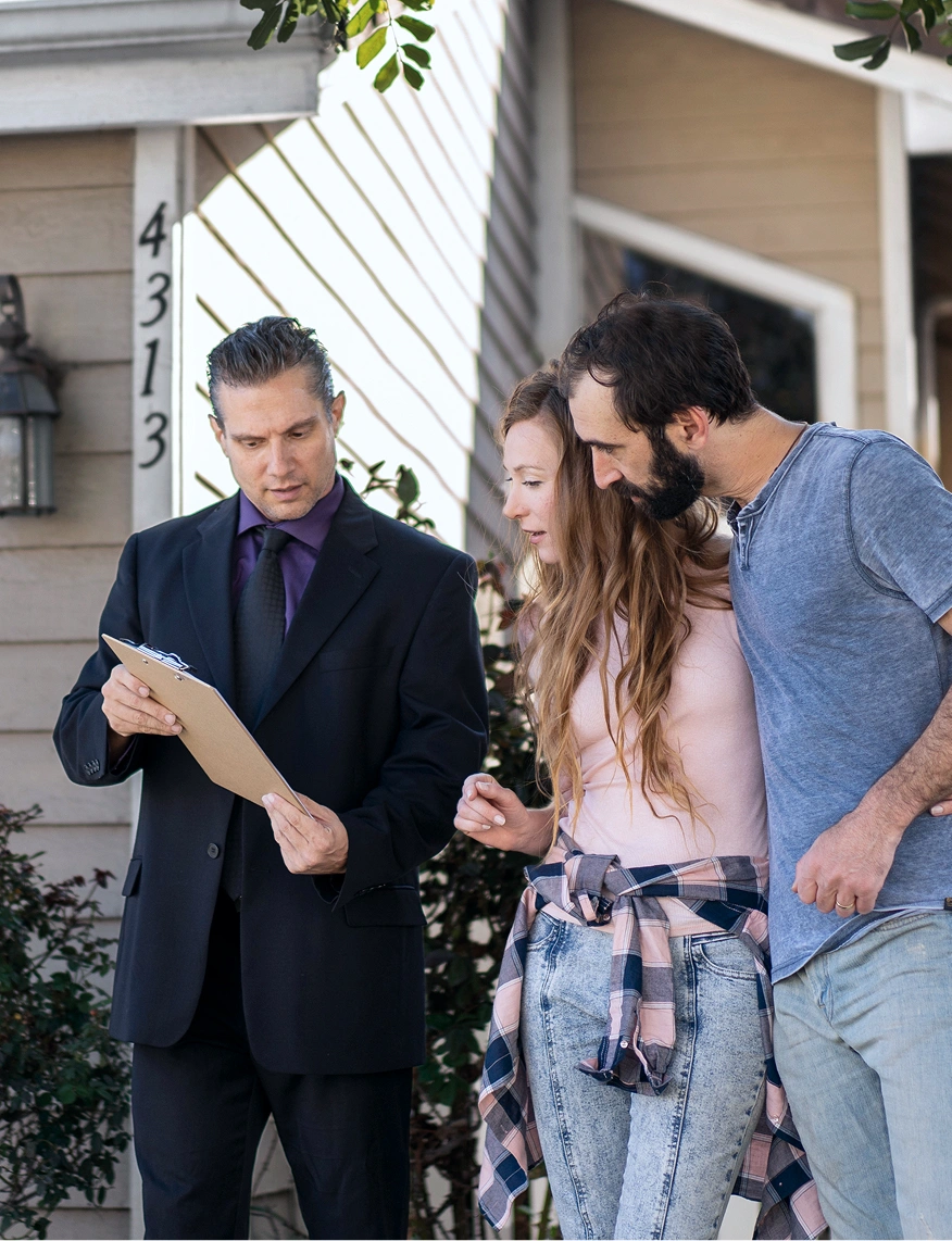 Property agent showing details to a couple outside a home